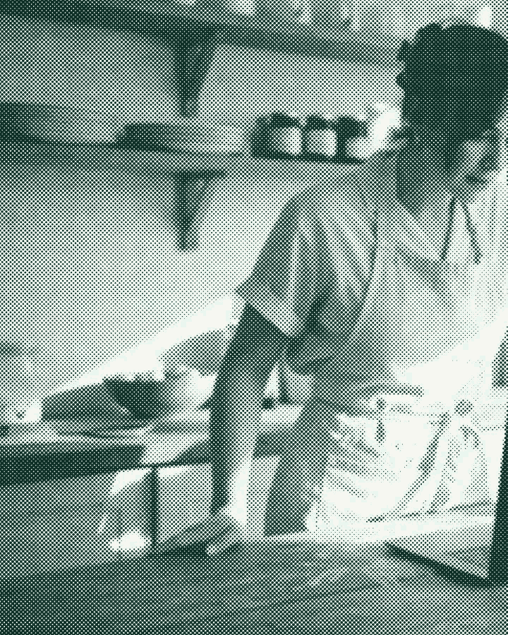 A baker at her counter, checking a laptop between orders